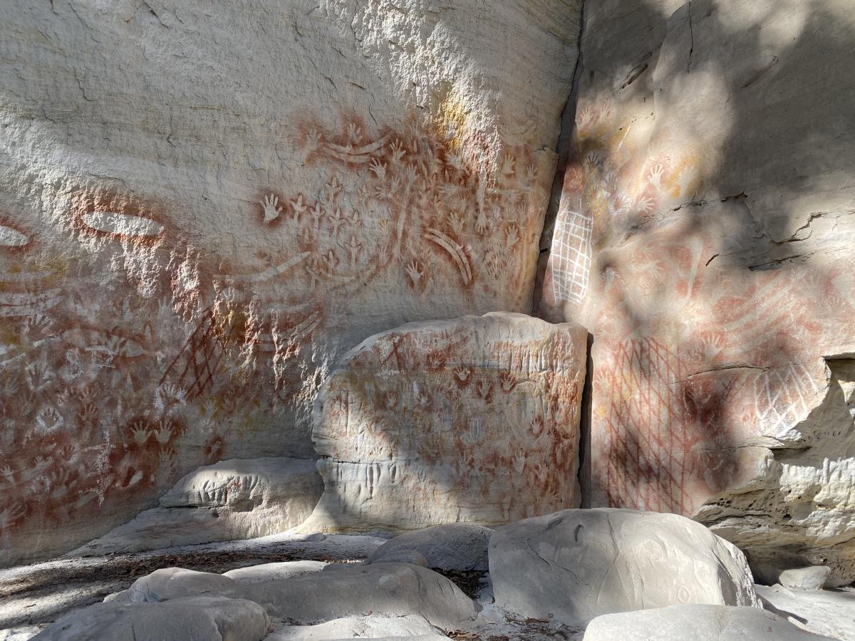 Aboriginal rock art with hand stencils painted on sandstone rock walls